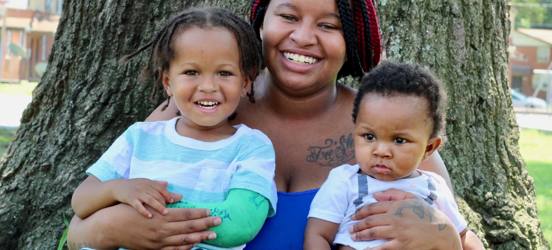 African American mother smiling outside with her two children