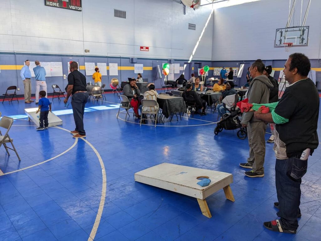 Many people inside a gym take part in discussions and activities.