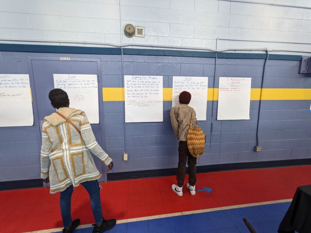 Two people read the handwritten text taped to a wall.