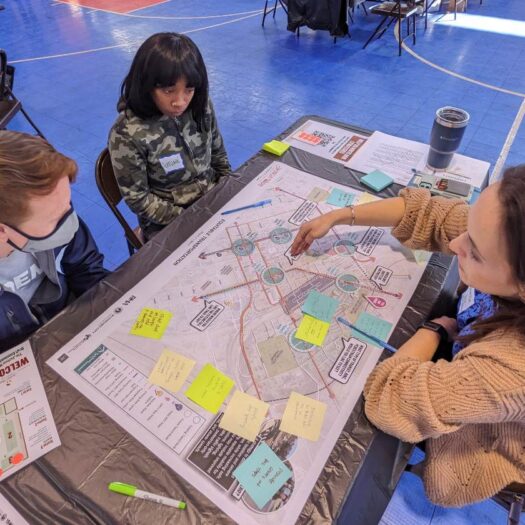 Three people sitting at a table and discussing a map