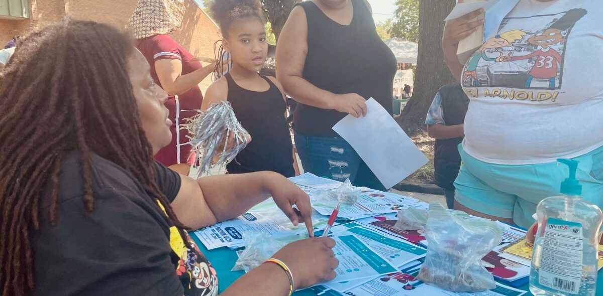 A Gilpin Informed Resident listens to residents at one of the communications tables they have been setting up around the neighborhood