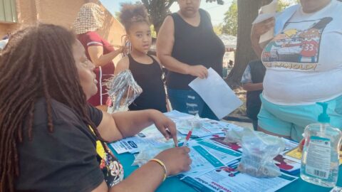 A Gilpin Informed Resident listens to residents at one of the communications tables they have been setting up around the neighborhood