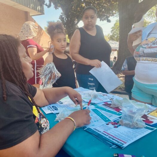 A Gilpin Informed Resident listens to residents at one of the communications tables they have been setting up around the neighborhood