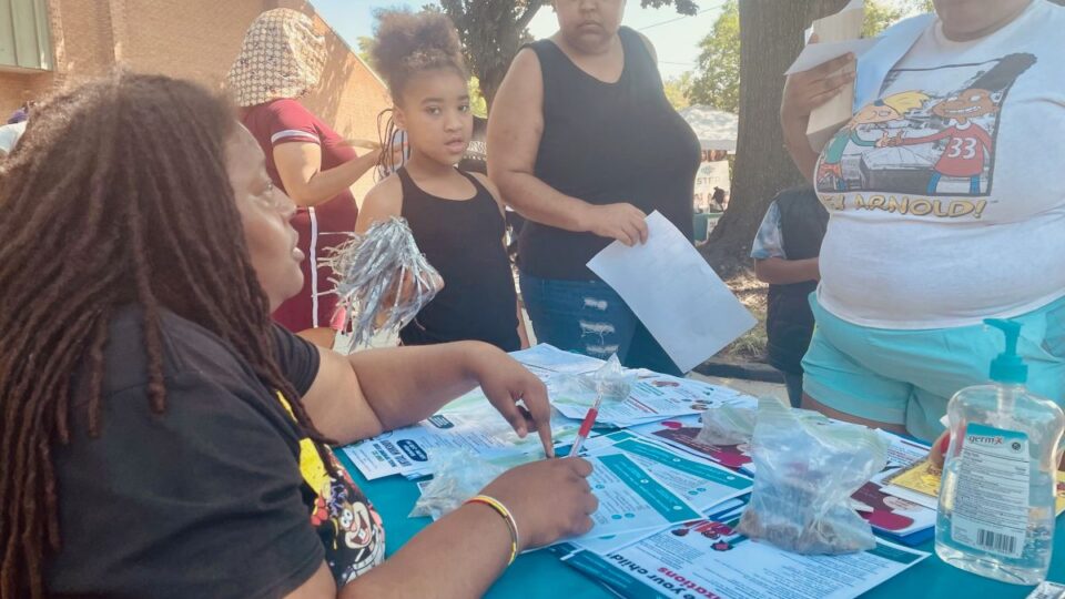 A Gilpin Informed Resident listens to residents at one of the communications tables they have been setting up around the neighborhood
