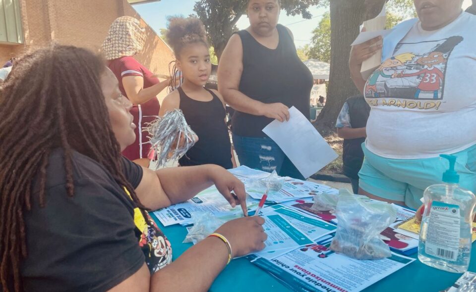 A Gilpin Informed Resident listens to residents at one of the communications tables they have been setting up around the neighborhood