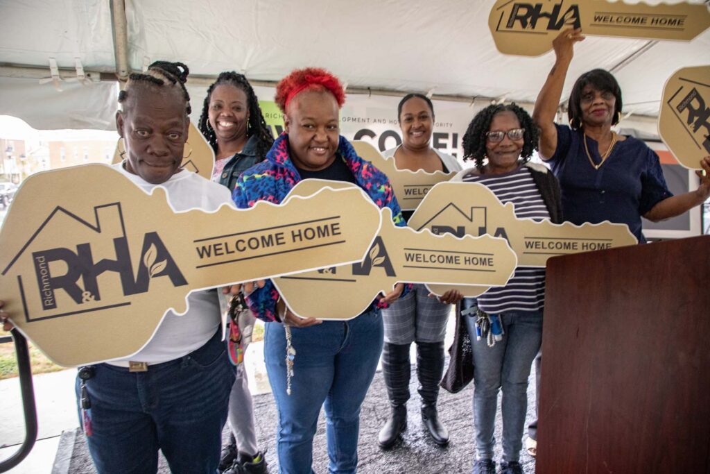 A group celebrating while holding large novelty keys reading "welcome home"