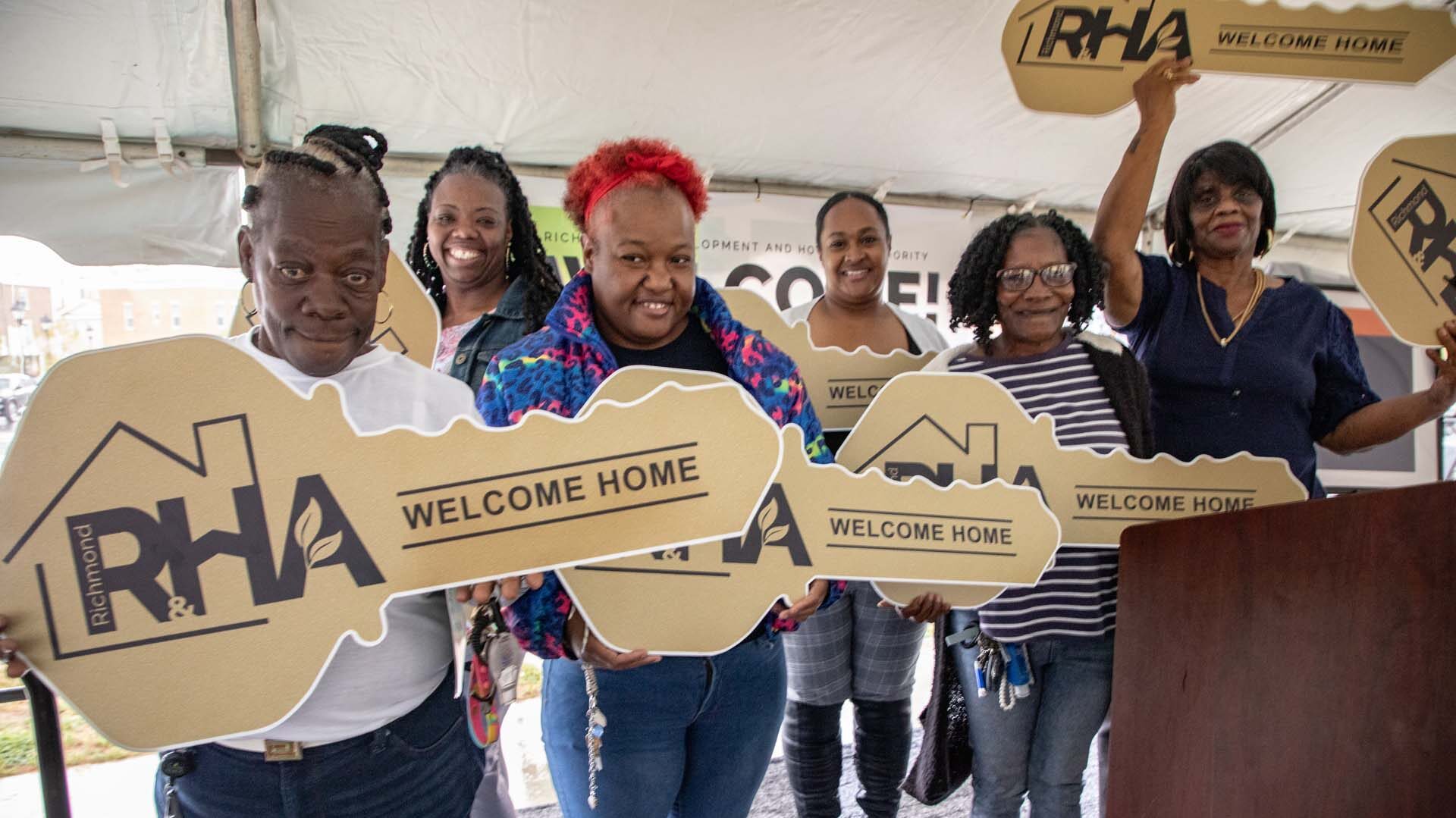 A group celebrating while holding large novelty keys reading "welcome home"