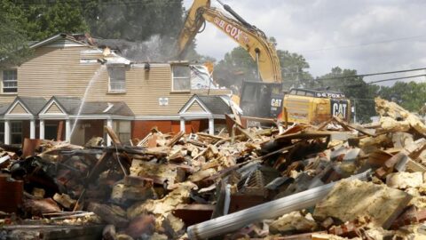 A construction vehicle demolishing an old home.